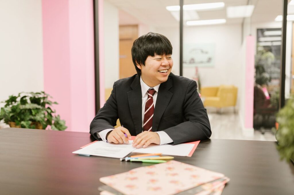 A cheerful businessman in a suit smiling while working in a modern office environment.